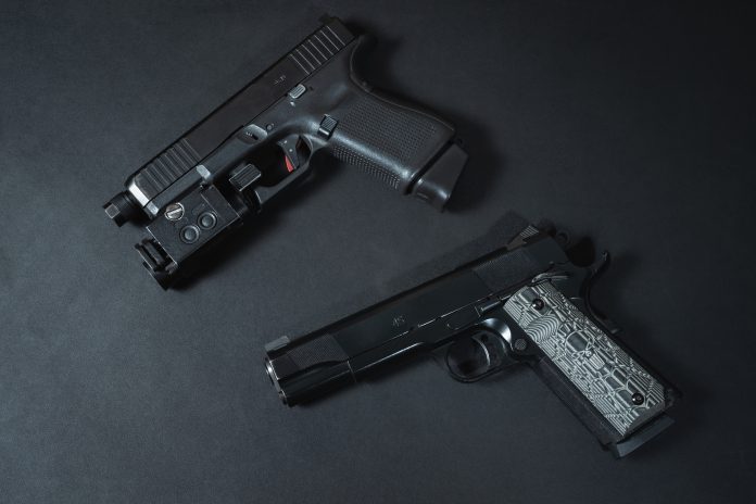 Two pistols of caliber 9mm and 45acp, close-up photo on a black background.